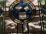 a close up of a stained glass window with a cross on it