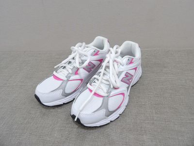 pair of white and pink running shoes on a gray surface