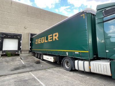 a green semi truck parked in front of a building