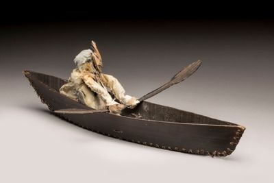 sculpture représentant un homme dans un canoë avec un chien à bord