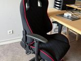 une chaise de bureau noire et rouge devant un bureau d'ordinateur
