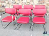 quatre fauteuils en cuir rouge disposés devant un mur de pierre