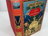 an old book with a red cover sitting on top of a white table