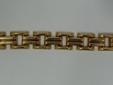 a close up of a gold bracelet on a white surface