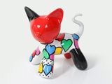 a cat figurine with hearts on it on a white surface