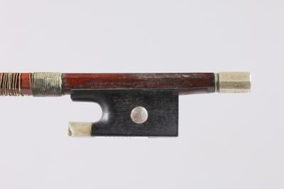un gros plan d'un archet de violon posé sur une surface blanche