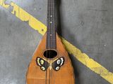une personne debout à côté d'une guitare sur laquelle est peint un visage