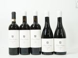 six bouteilles de vin sont alignées sur une surface blanche