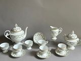 a group of white and gold tea set on a table