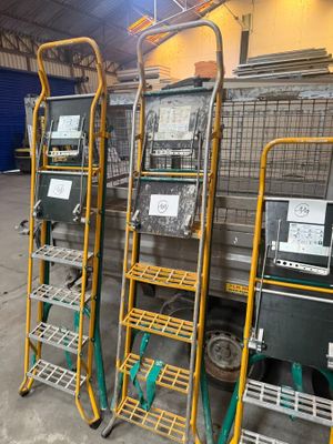 three metal racks with laptops on them in a warehouse