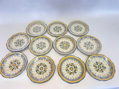huit assiettes ornées de motifs jaunes et bleus sont disposées sur une surface blanche