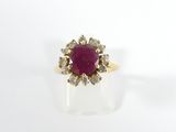 a close up of a gold ring with a ruby stone surrounded by diamonds