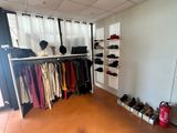 an image of a room with a rack of clothes and shoes