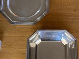 two silver plates on a wooden table next to a bag of candy