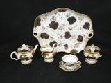 an image of a white and gold tea set on a black background
