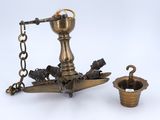 an antique brass oil lamp with a chain around it and a cup on the ground