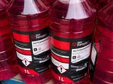 Des bouteilles contenant un liquide rouge sont posées sur une étagère dans un magasin.