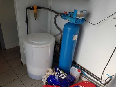 a blue water softener tank and a blue water softener tank in the corner of a kitchen
