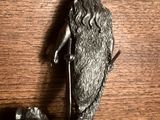 une statue représentant un homme barbu, coiffé d'un chapeau, posée sur une table en bois