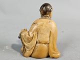 a close up of a figurine of a person sitting on the ground