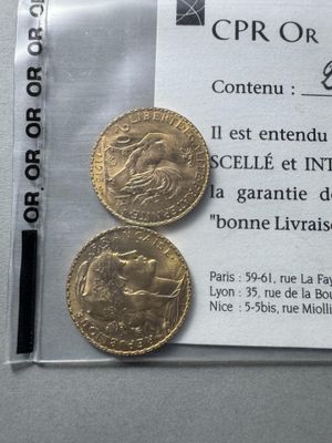 two gold coins sitting on top of a piece of paper