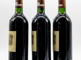 three bottles of wine sitting next to each other on a white surface