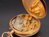 a gold pocket watch sitting on a black surface