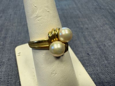 une bague en or ornée de trois perles, posée sur une serviette