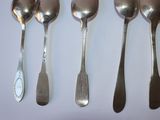 four spoons and a spoon spoon are lined up on a white surface