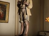 a statue of a boy standing on a table with a vase of flowers