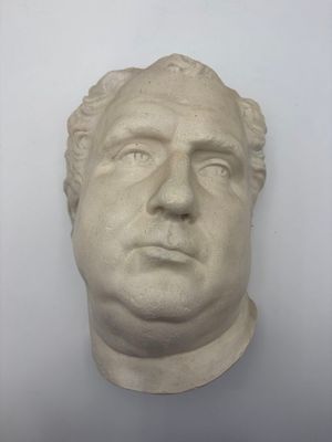 plaster bust of a man ' s head on a white wall