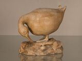 sculpture représentant un canard posé sur un rocher, posée sur une table en verre