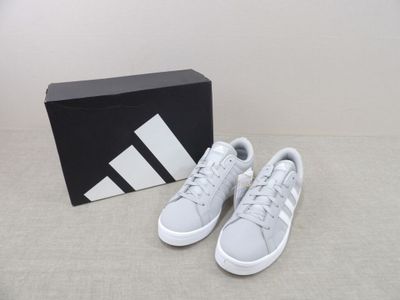 Les baskets adidas sont dans une boîte posée par terre.
