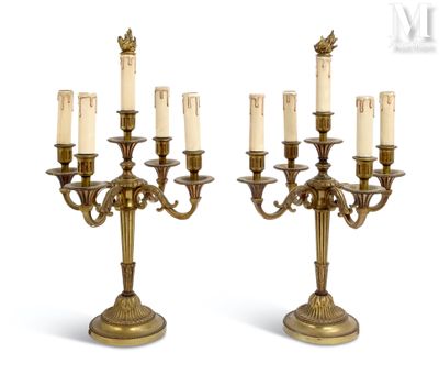une paire de chandeliers anciens en laiton, chacun orné d'une bougie