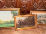 trois tableaux encadrés posés sur un banc en bois devant un mur