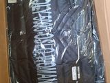 black t - shirt in a cardboard box with a white logo on it
