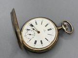 a gold pocket watch with roman numerals on it