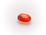 a close up of an orange gemstone on a white surface