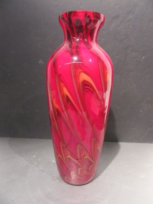 un vase en verre rose orné d'un motif rouge en spirale