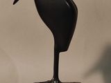 a black bird statue on a white base on a gray background