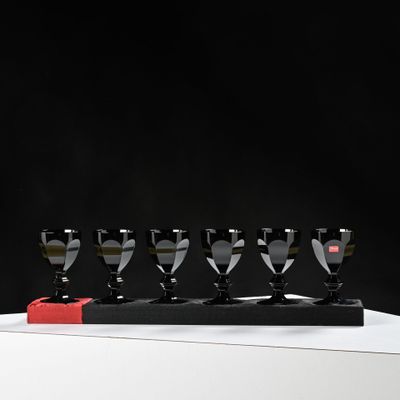 four black and white wine glasses are lined up in a row