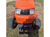 an orange lawn mower sitting on top of a grass covered field