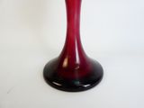un vase rouge posé sur une table blanche