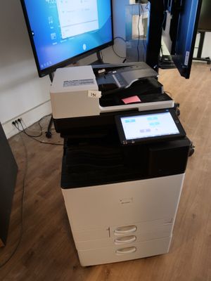 a printer sitting on top of a desk in front of a monitor