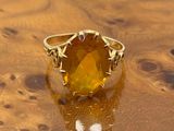 a close up of a ring with a yellow stone on top of a wooden table