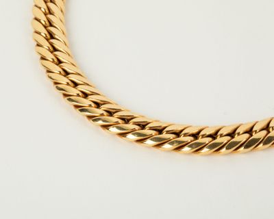 a close up of a gold necklace on a white surface