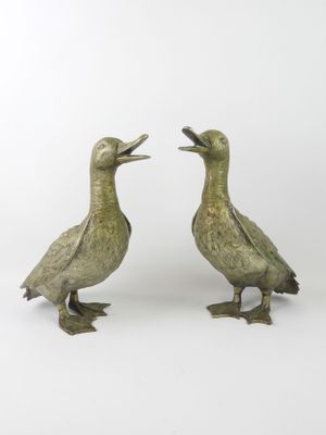 pair of bronze ducks on feet with open beaks on a white background