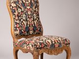une chaise dont le dossier est recouvert d'un tissu à motifs floraux et dont la structure est en bois