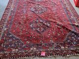 un tapis posé au sol dans une pièce où se trouvent des chaises, dont une rouge