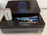 a black box with pens, pencils, and a cell phone on top of it